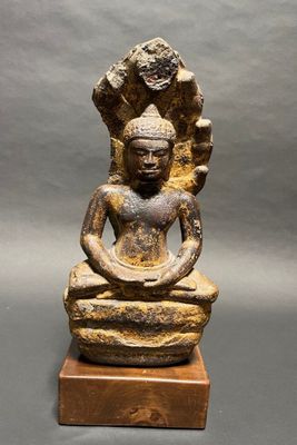 an old statue of a buddha sitting on a wooden base
