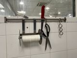 a pair of scissors hanging on a wall with a roll of thread