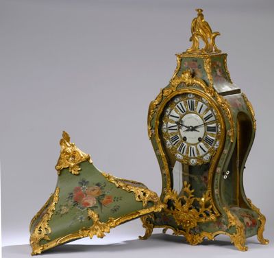 une horloge verte et dorée posée à côté d'un parapluie vert et doré