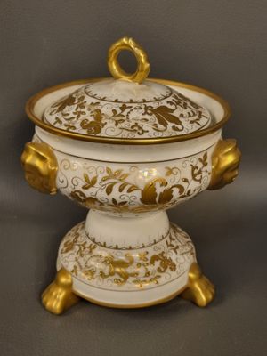 an image of a white and gold covered bowl on a stand