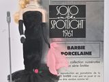 une poupée Barbie en robe noire, avec un sac à main rose et un micro