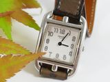 a watch sitting on a table with a leaf in the background