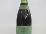 an old bottle of wine sitting on top of a white table