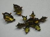 trois perles de verre vertes et marron sur un fond blanc