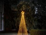 lighted christmas tree in front of a house in the rain