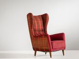 une chaise rouge avec un coussin à carreaux et des pieds en bois, dans une pièce blanche