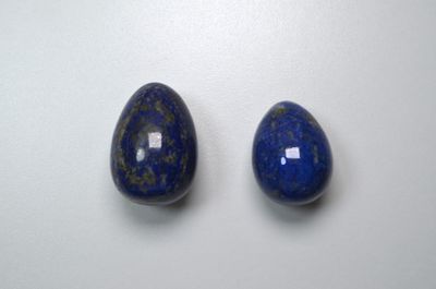 two blue lapis stone beads on a white surface