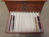 a wooden box with pens and a pen in it