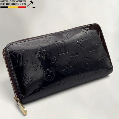 the louis vuitt wallet is black and has a gold zipper