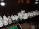 a lot of coffee cups on a shelf in a room