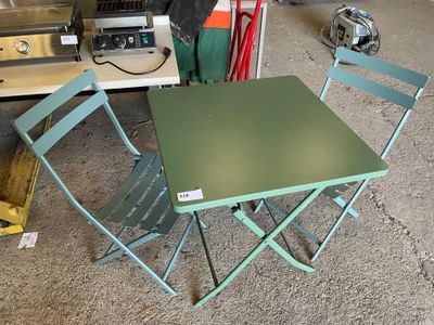une table verte et deux chaises dans un garage