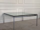 une photo d'une table basse en verre et chrome dans une pièce blanche