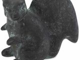 statue d'un chat assis sur ses pattes arrière sur une surface blanche