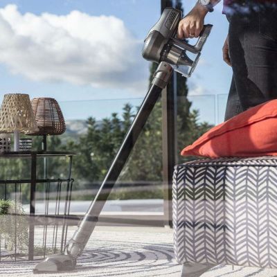 une femme en train d'utiliser un aspirateur sans fil sur une terrasse