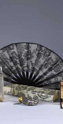 lace fan, perfume, and perfume bottle on a white surface