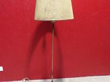une lampe posée par terre devant un mur rouge