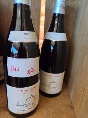 trois bouteilles de vin sont posées sur une étagère en bois devant une bouteille de vin