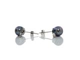 une paire de boucles d'oreilles en perles noires posées sur une surface blanche