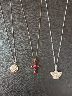 three necklaces with charms on them sitting on a black surface