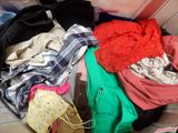 a pile of clothes sitting on a couch next to a laptop