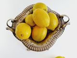 a bowl of lemons on a white table with a few lemons