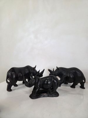 trois figurines de rhinocéros noirs posées sur une surface blanche