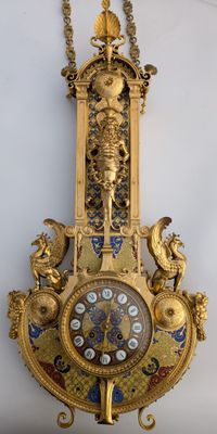 a gold clock hanging on the wall with a chain