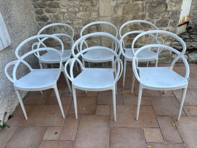 four white chairs sitting in front of a stone wall