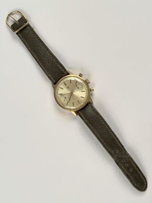 une image représentant une montre posée sur une surface blanche, avec un bracelet noir