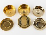 four different types of brass plates and lids on a white surface