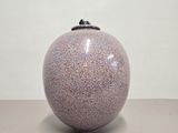 un vase violet avec un couvercle noir posé sur une table