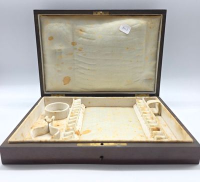 une vieille boîte en bois contenant une petite tasse, posée sur une surface blanche