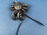 silver broochle with black stones on a blue background
