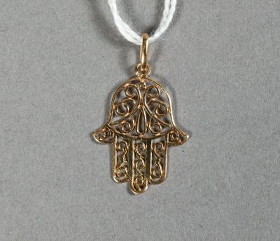 un pendentif en forme de main de Hamsa dorée, muni d'un cordon blanc, sur fond gris