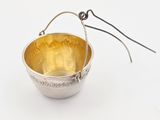 an image of a silver bowl with a handle on a white surface