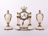 trois vases blancs et dorés et une horloge posés sur une table