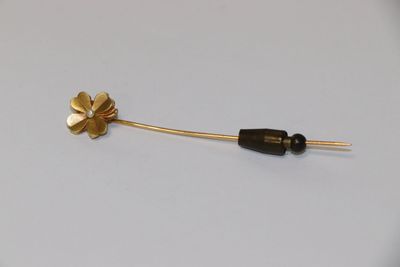 un gros plan d'une broche en forme de fleur en or ornée d'une perle noire