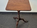 a small table with a wooden top on a tile floor