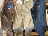 trois paires de pantalons pour homme posées sur une palette en bois