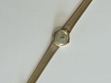 a gold wrist watch on a white surface with a white background