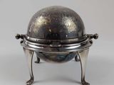 un vieux plateau en argent orné d'un globe terrestre, posé sur un socle