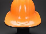 an orange hard hat sitting on top of a black base