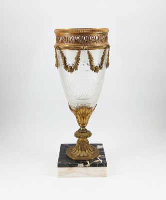 a gold and white glass vase on a marble base