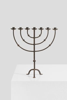 a metal menorah on a white pedestal with a gray background