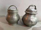 two silver pots sitting next to each other on a table