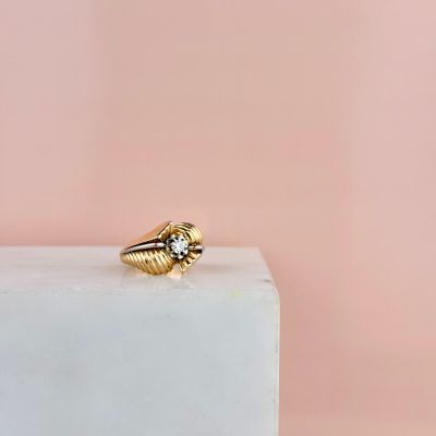 une bague en or posée sur un bloc de marbre blanc