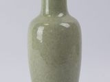 un vase vert posé sur un socle, sur une surface blanche
