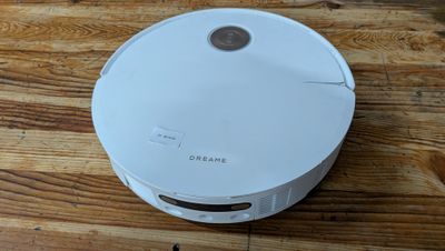 un robot blanc assis sur un plancher en bois
