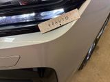 the front end of a white car with a sticker on it ' s bumper