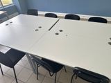 a white table with black chairs in a room with blue walls